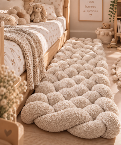 Tapis tressé rembourré beige en tissu bouclette au pied d’un lit enfant