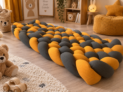 Tapis tressé rembourré moutarde et gris foncé au pied d’un lit enfant
