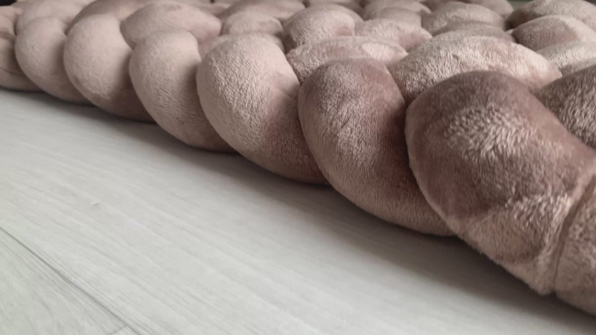 Tapis tressé rembourré moka en tissu minky doudou au pied d’un lit enfant